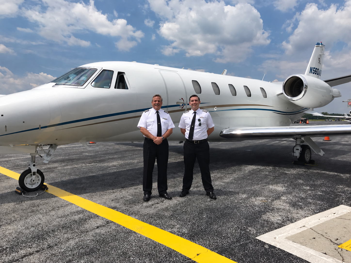 Two pilots in uniform standing infront of cabin door of Citation Excel N560AD